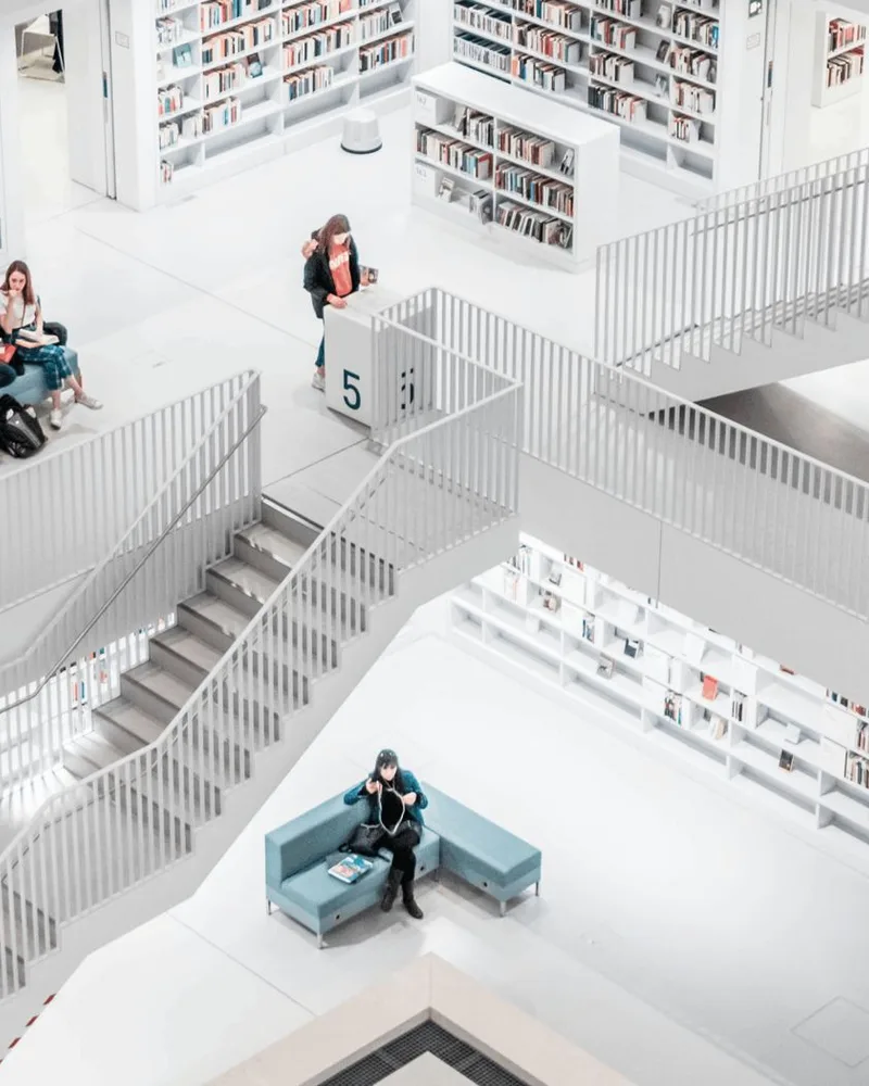 Lower floors of the same library, teal sofa among white shelves