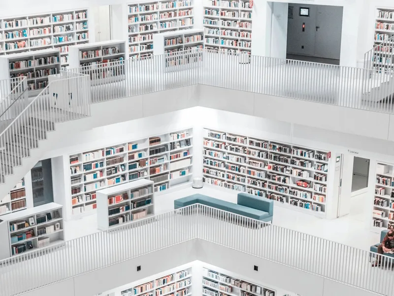 Upper floors of a modern white library with teal seating