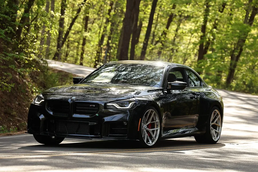 Black BMW M2 carving a tree-lined mountain road