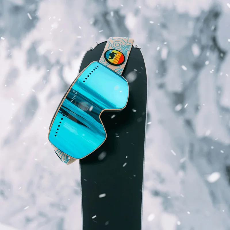 Goggles resting on a snowboard in falling snow
